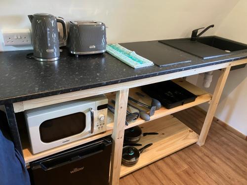 a counter top with a microwave on a table at Pod Lois in Dolgellau