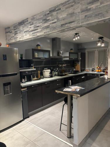 une cuisine avec des appareils en noir et blanc et un comptoir dans l'établissement Maison pour les 24 h du Mans, à Arnage