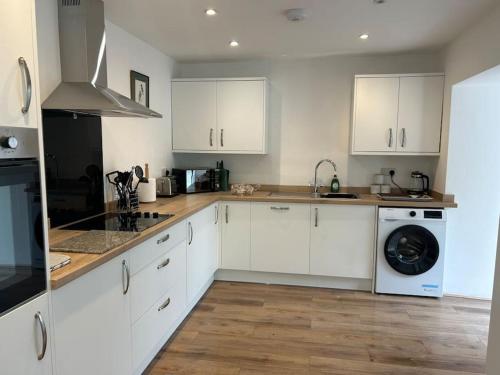 a kitchen with white cabinets and a washer and dryer at Kimberly House in Arthog
