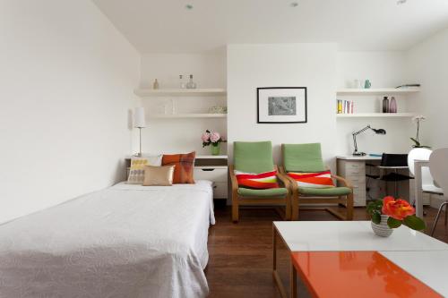a bedroom with a bed and two chairs and a desk at 118 Brondesbury Road Apartments in London