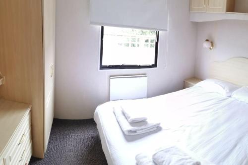 a small bedroom with a white bed and a window at 3 Bedroom Caravan in Rural area - Tennyson in Porchfield