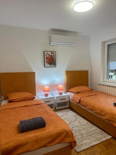 een slaapkamer met 2 bedden met oranje lakens en lampen bij Vila Mariam&Maid in Sarajevo