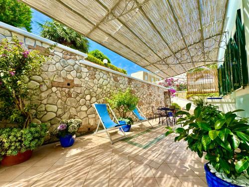 a patio with blue chairs and a stone wall at PonzaSmeralda Le Forna in Ponza