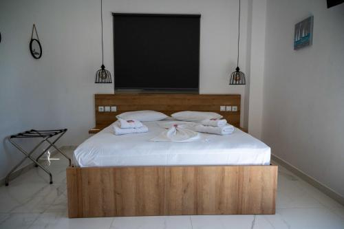 a bedroom with a wooden bed with towels on it at Finikas Suites & Apartments Airport By Airstay in Artemida