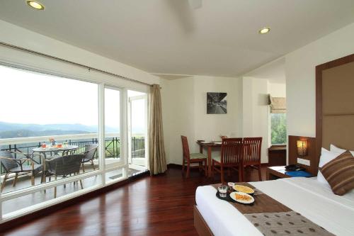 a bedroom with a bed and a balcony with a table at Sterling Ooty Fern Hill in Ooty