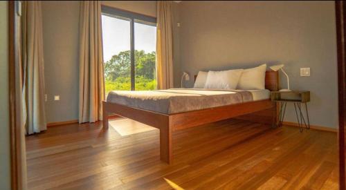 a bedroom with a bed with a large window at Houttuyn Wellness River Resort in Paramaribo