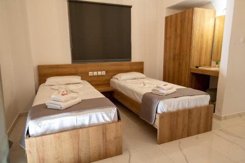 two twin beds in a room with a television at Finikas Suites & Apartments Airport By Airstay in Artemida