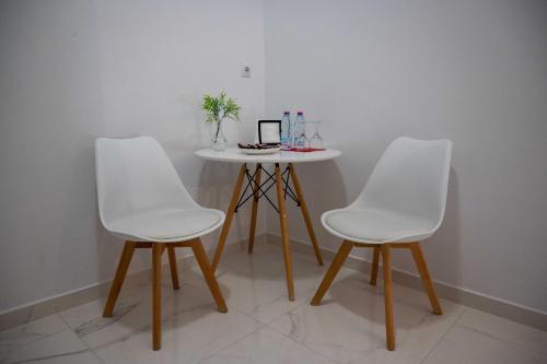 a table with two white chairs and a table with at Finikas Suites & Apartments Airport By Airstay in Artemida