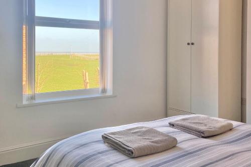 a bedroom with two towels on a bed with a window at BeRo Terrace, only a minutes walk to the beach! in Withernsea