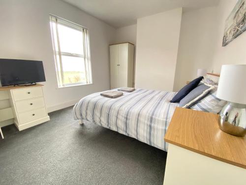 a white bedroom with a bed and a television at BeRo Terrace, only a minutes walk to the beach! in Withernsea