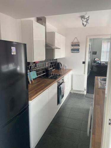 a kitchen with white cabinets and a black refrigerator at BeRo Terrace, only a minutes walk to the beach! in Withernsea