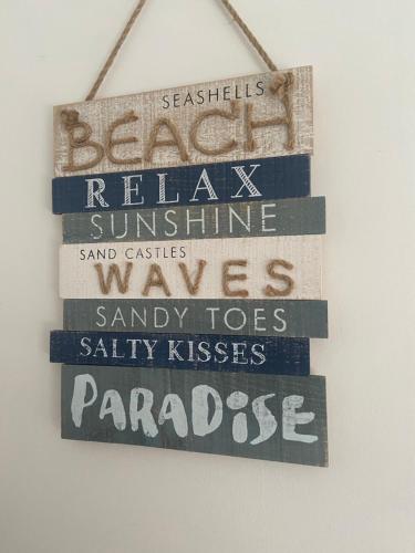 a sign that reads beach relax sunshine sand castles waves sandy toes salty kissesparaza at BeRo Terrace, only a minutes walk to the beach! in Withernsea