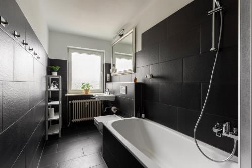 a black bathroom with a tub and a sink at Global Living - Design Apartments I Terrace I Kitchen I Smart-TV I Parking space I München in Munich