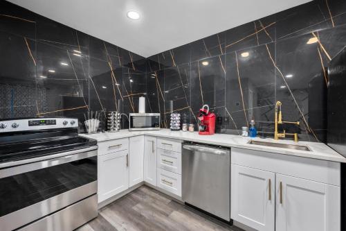 a kitchen with white cabinets and black tiles at Stylish 2-BR Getaway in Heights with Pool in Houston