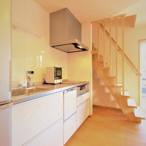 a kitchen with white cabinets and a staircase at 白馬パウダーマウンテン in Hakuba