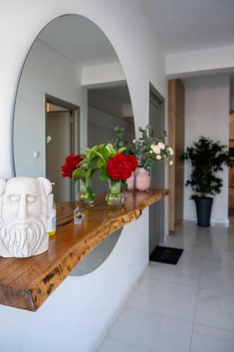 a room with a table with flowers and a mirror at Finikas Suites & Apartments Airport By Airstay in Artemida