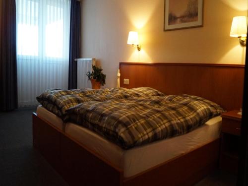 a bedroom with a bed with a plaid blanket at Landhotel Wilhelm Busch in Lüthorst