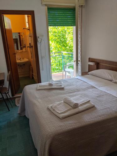 a bedroom with a bed with two towels on it at Hotel Bellevue in Cesenatico