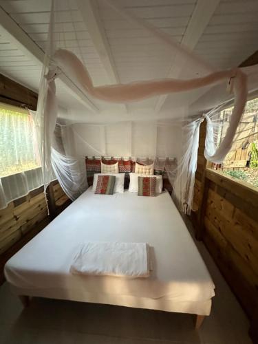 a large white bed in a tent with two windows at Rêve de Cabane in Capesterre-de-Marie-Galante