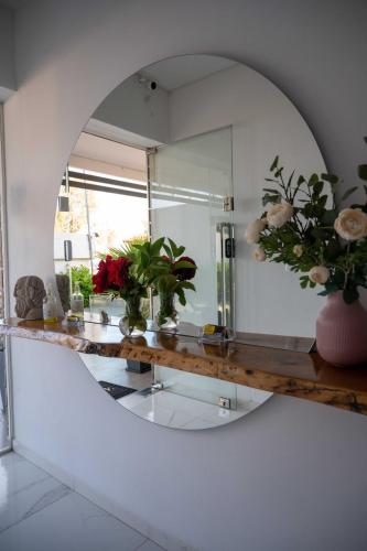 a mirror in a bathroom with flowers on a counter at Finikas Suites & Apartments Airport By Airstay in Artemida