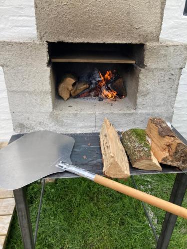 a grill with a spatula and a fire in it at Glædegården -Glaede Landhof- 12 beds! in Frøstrup