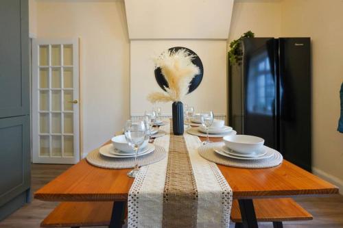 a dining room table with plates and wine glasses at Orchard Bungalow - Sleeps 10 - Close to Town Centre - Free Parking, Pool Table, Fast Wi-Fi and Smart TV with Netflix by Yoko Property in Northampton