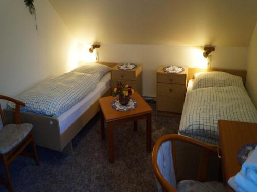 two beds in a room with a table and two chairs at Landhotel Wilhelm Busch in Lüthorst