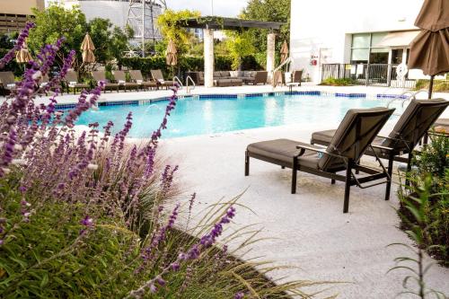 a swimming pool with two chairs and purple flowers at The Westin Austin at The Domain in Austin