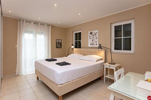 a bedroom with a large white bed and a desk at Family-friendly apartments with swimming pool Vinisce, Trogir - 22873 in Vinišće