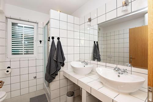 a white bathroom with two sinks and a mirror at Family-friendly apartments with swimming pool Vinisce, Trogir - 22873 in Vinišće