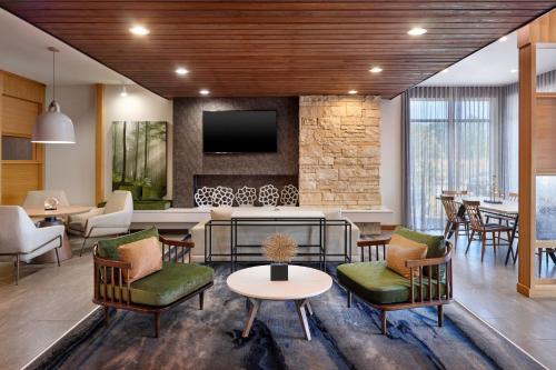 a lobby with chairs and tables and a tv at Fairfield Inn & Suites Locust Grove I-75 South in Locust Grove