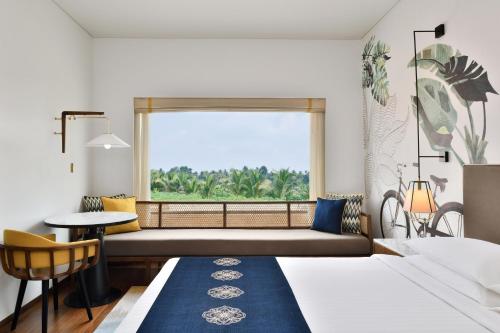 a hotel room with a bed and a window at Port Muziris, A Tribute Portfolio Hotel by Marriott in Nedumbassery