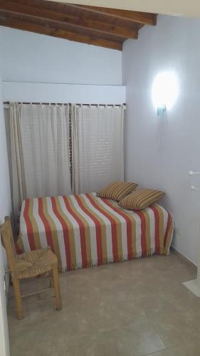 a bedroom with a striped bed and a chair at El Naranjo in Chascomús