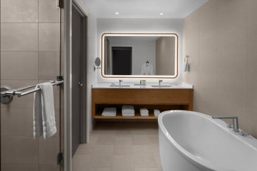 a bathroom with a tub and a sink and a mirror at The Westin Atlanta Gwinnett in Duluth