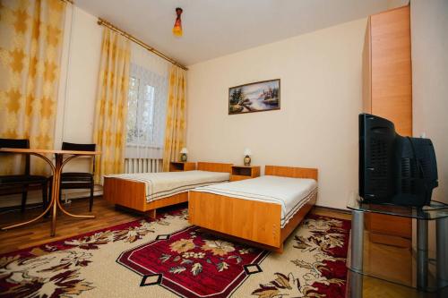 a bedroom with two beds and a flat screen tv at Hotel Uyut in Kremenchuk
