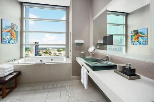 a bathroom with a tub and a sink and a window at AC Hotel by Marriott Charlotte City Center in Charlotte