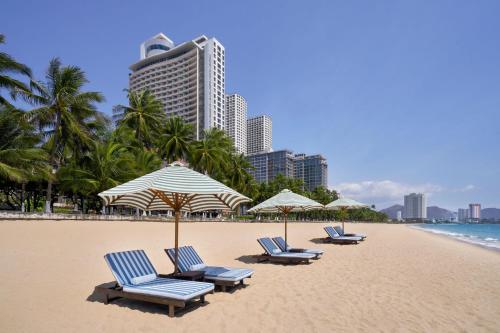 un grupo de sillas y sombrillas en una playa en Sheraton Nha Trang Hotel & Spa en Nha Trang