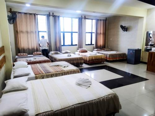 a group of beds in a room with windows at Casa Nativa Iquitos in Iquitos