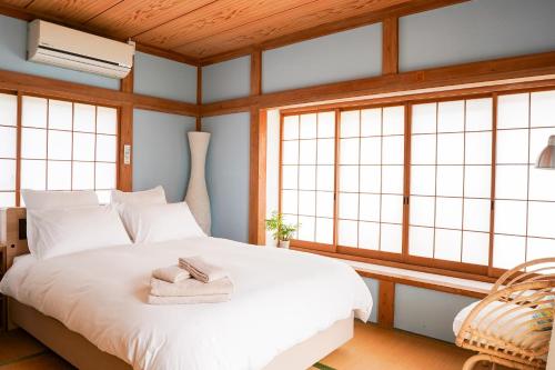 a bedroom with a white bed with towels on it at ONJUKU BEACH COTTAGE - private house 1 min walk to beach in Onjuku