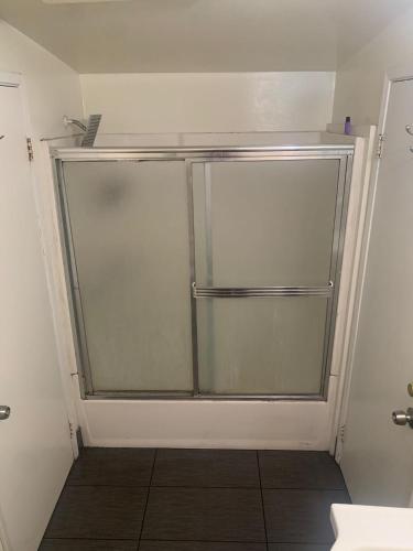 a glass shower door in a bathroom with a tile floor at LA Love Home in Los Angeles