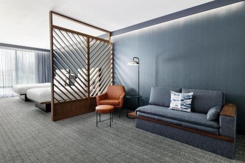 ニューキャッスルにあるCourtyard by Marriott New Castleのソファ、椅子、ベッドが備わる客室です。