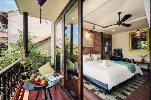 a bedroom with a bed and a table with a bowl of fruit at Art Museum Villa Hoi An in Hoi An