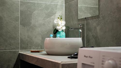 a bathroom sink with a vase of flowers on a counter at Pension Irivai appartement "Uparu" 1 chambre bord de mer in Uturoa