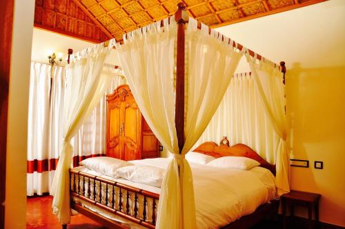 a bedroom with a canopy bed with white curtains at Hanging Huts Resorts in Kotagiri