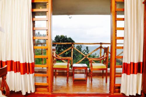 a room with a balcony with a large window at Hanging Huts Resorts in Kotagiri