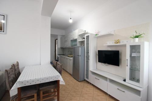 a kitchen with a table and a tv in it at Garden Vila Ermali in Ksamil