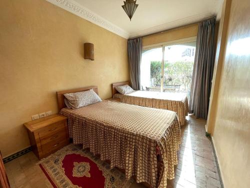 two beds in a room with a window at Villa plage tiguert résidence les méridiennes in Agadir