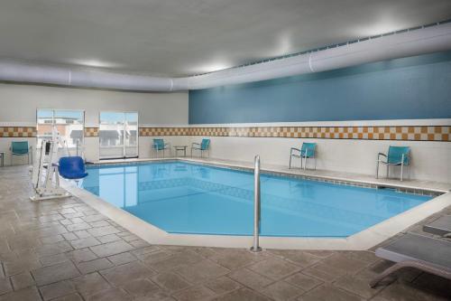 a large swimming pool with blue chairs in a room at TownePlace Suites Dallas DeSoto in DeSoto