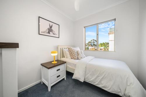 a white bedroom with a bed and a window at In The Midst on Melbourne in Adelaide