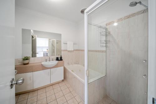 a bathroom with a shower and a sink and a tub at In The Midst on Melbourne in Adelaide